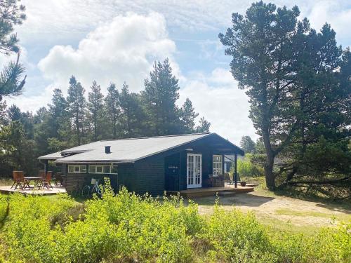 una pequeña casa azul en un campo con árboles en 8 person holiday home in R m, en Kongsmark