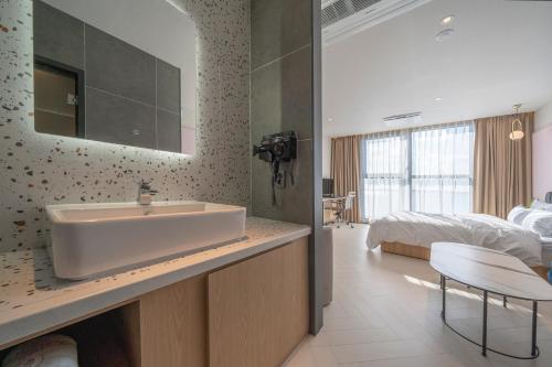 ein Bad mit einem Waschbecken und ein Bett in einem Zimmer in der Unterkunft Brown Dot Siheung Geobuksum in Siheung