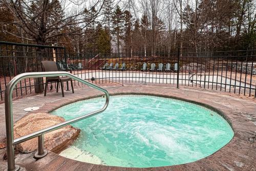 a small swimming pool with a metal railing in a yard at Tremblant-Les-Eaux Le Contemporain by Gestion ELITE in Mont-Tremblant