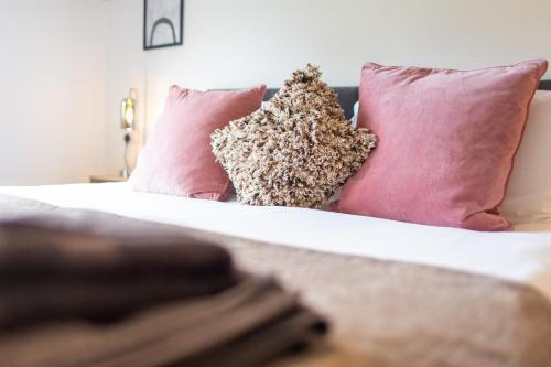 a white bed with pink pillows and a sqor at Maltings House Cosy and Stylish 2 bedroom flat near the city centre with free parking and ensuite rooms in Carlisle