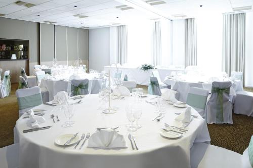 a conference room with white tables and chairs with silverware at Novotel Newcastle Airport in Newcastle upon Tyne
