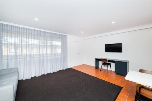 a living room with a couch and a desk with a television at River Motel in Queanbeyan