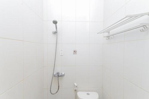 a white bathroom with a shower and a toilet at RedDoorz near BG Junction Surabaya in Surabaya
