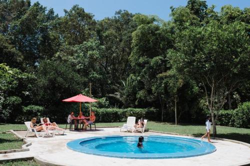 a group of people sitting around a swimming pool at El Campito Lodge in Ayampe