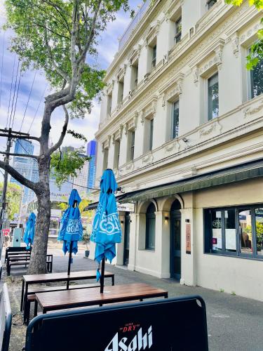 two blue umbrellas on a table in front of a building at Clarendon Hotel in Melbourne