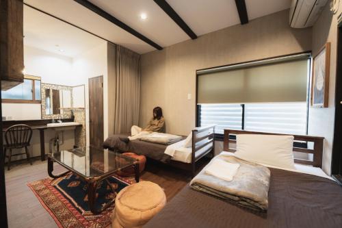 a room with two beds and a woman sitting on a desk at Traditional Apartment Takamatsu Guesthouse in Takamatsu