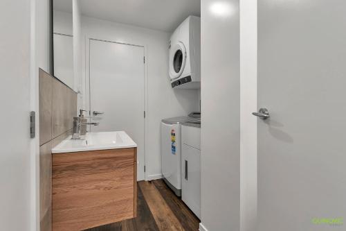 a white bathroom with a sink and a microwave at QV Stays Upscale Modern Getaway in Auckland