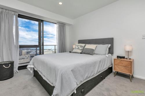 a bedroom with a large bed and a large window at QV Stays Upscale Modern Getaway in Auckland