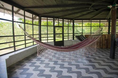 a hammock in a pavilion with a room with windows at Casa Finca Villa Laura in Leticia