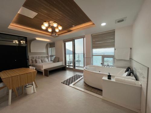 a bathroom with a tub and a table and a couch at Somewhales Pension in Namhae