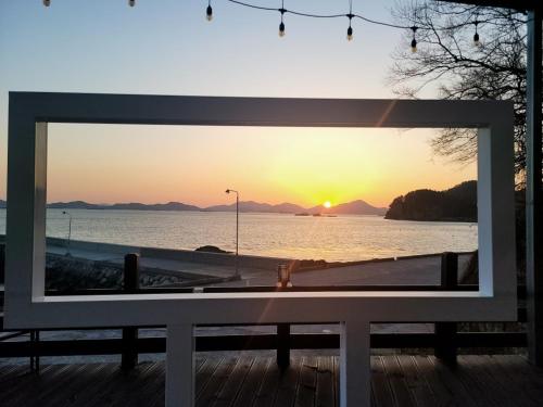 a view of the sunset through a window of a bench at Somewhales Pension in Namhae