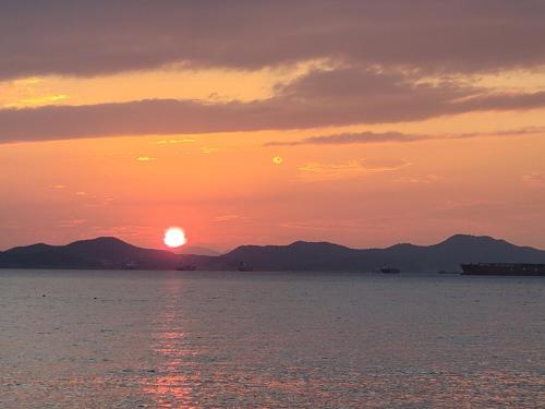 a sunset over the water with mountains in the background at Somewhales Pension in Namhae