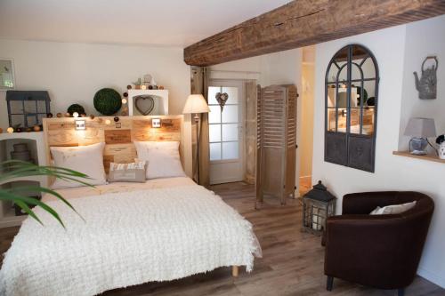 a bedroom with a large bed and a chair at Le Clos de la Chouette in Pommard