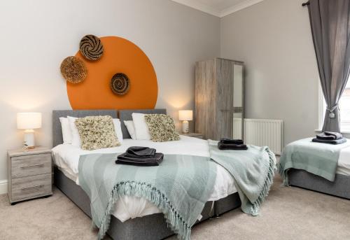 a bedroom with a large bed with an orange headboard at Logan House, Modern and Spacious Townhouse close to City Centre in Carlisle