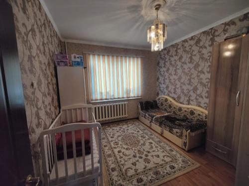 ein Schlafzimmer mit einem Kinderbett und einem Sofa in einem Zimmer in der Unterkunft 3-х комнатная квартира in Almaty