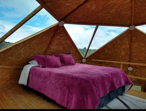 Bett in einem Zimmer mit einem großen Fenster in der Unterkunft GLAMPING Aldea Muisca in Tota