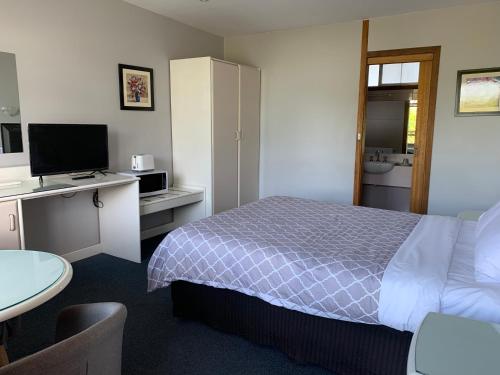 a hotel room with a bed and a desk with a television at Casey on Princes Motel in Hallam
