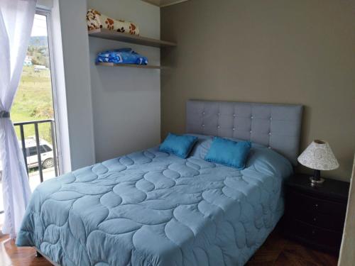 a bedroom with a large bed with blue pillows at APARTAMENTO BALCON DE LA ESPERANZA GUATAPE in Guatapé