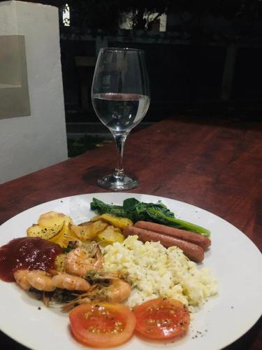 a plate of food with shrimp rice and a glass of wine at Sky View Cabin Unawatuna in Unawatuna