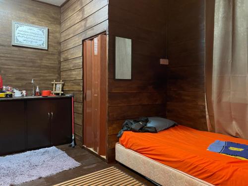 sypialnia z pomarańczowym łóżkiem i umywalką w obiekcie Hj Hassan Floating Cabin w mieście Kuala Terengganu