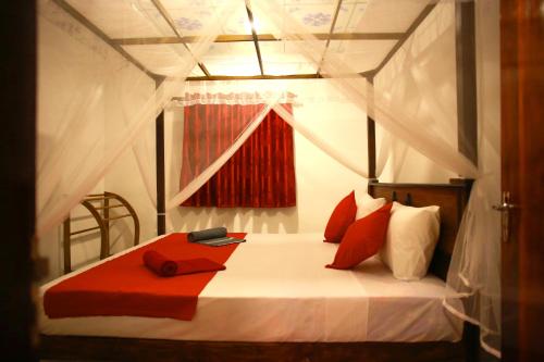 sypialnia z łóżkiem z białymi i czerwonymi poduszkami w obiekcie Coastal House w mieście Mirissa