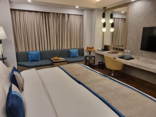 um quarto de hotel com uma cama grande e um sofá em The Piccadily em Lucknow