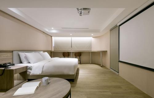 een hotelkamer met een bed en een projectiescherm bij Spring Rhapsody Hotel in Taichung