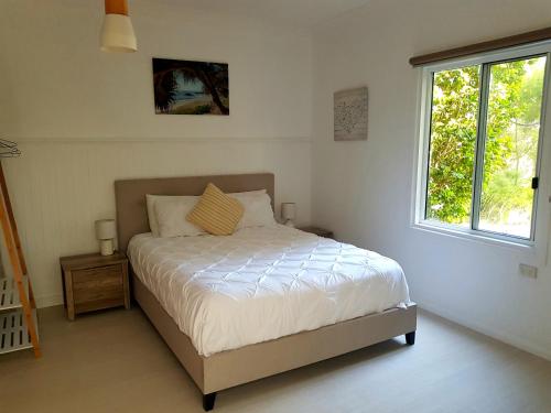 a bedroom with a bed and a window at Forest view bungalow in Nambucca Heads
