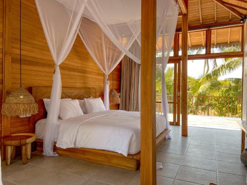 a bedroom with a bed with white sheets and curtains at Diamond Beach Villas in Nusa Penida