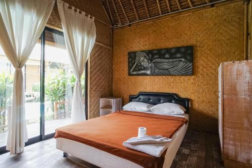 a bedroom with a bed and a large window at Moon Bamboo in Canggu