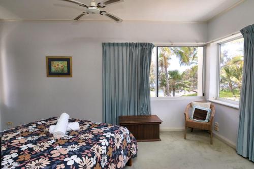 a bedroom with a bed and a window and a chair at Royle Palms unit 3 in Bargara