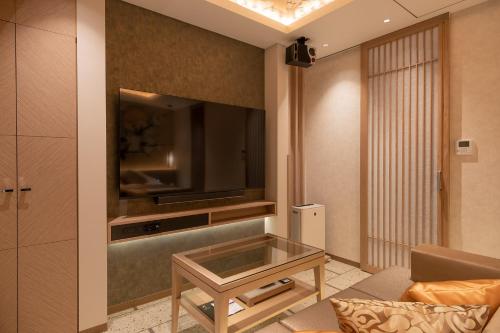 uma sala de estar com uma televisão, um sofá e uma mesa em HOTELみなと-MINATO- em Tóquio