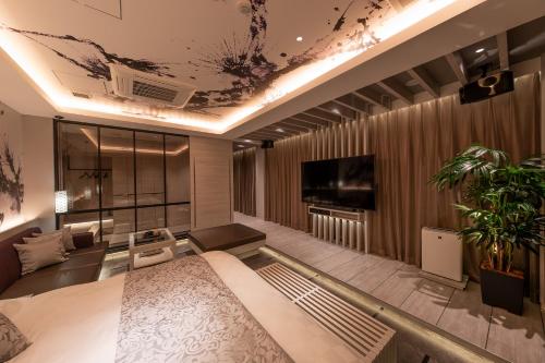 a living room with a bed and a tv at HOTELみなと-MINATO- in Tokyo