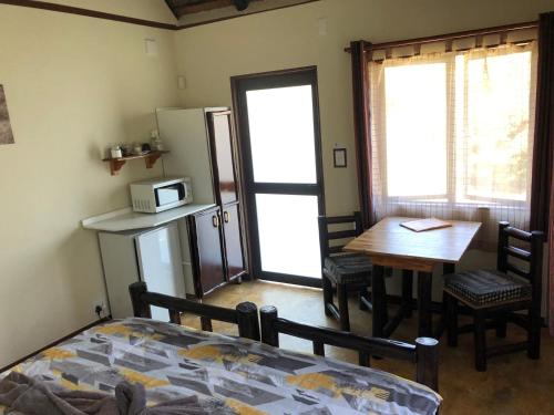 a room with a bed and a table and a refrigerator at Thokozani Lodge in White River