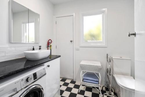 a white bathroom with a sink and a washing machine at On The Beach in Rosebud