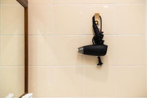 a black phone hanging on a white tiled wall at River Motel in Queanbeyan