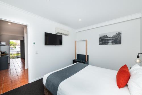 a bedroom with a bed and a flat screen tv at River Motel in Queanbeyan