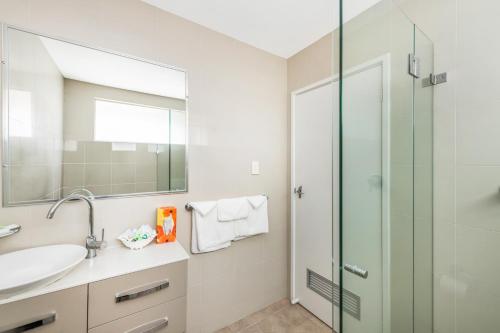a bathroom with a sink and a glass shower at River Motel in Queanbeyan