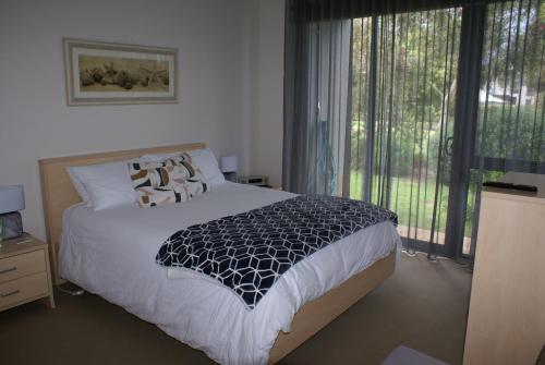a bedroom with a bed and a large window at Torquay Golf Retreats - Pool, Beach, Tennis, Golf in Torquay