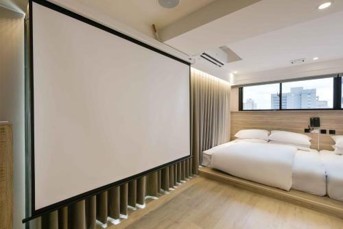 a large screen in a bedroom with a bed at Spring Rhapsody Hotel in Taichung