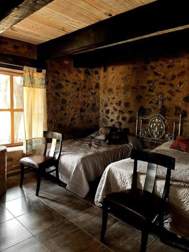 a bedroom with two beds and two chairs in it at Casa Corazón in Celaya