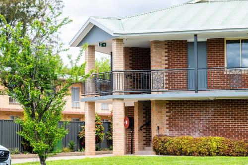 a brick building with a balcony and a tree at River Motel in Queanbeyan