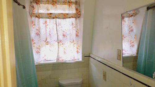 a bathroom with a toilet and a window at Mini Mansion Hotel near public transportation is the yellow and green house on the corner of 8th st and Madison avenue in Plainfield