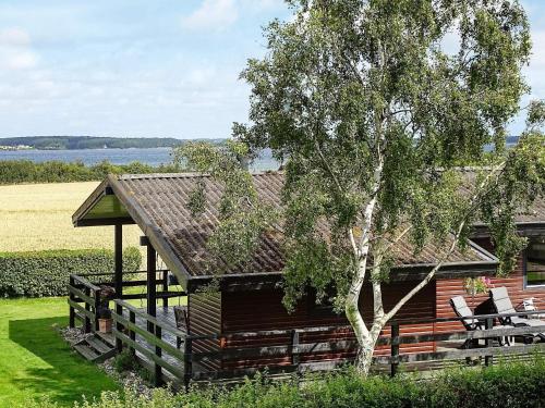 スベンボーにある8 person holiday home in Svendborgの木と椅子が前に置かれたキャビン