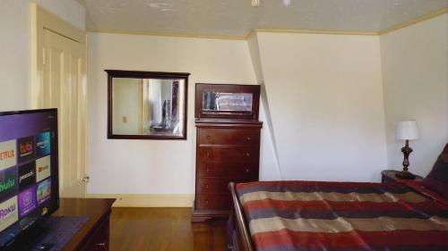 a living room with a television and a dresser at Mini Mansion Hotel near public transportation is the yellow and green house on the corner of 8th st and Madison avenue in Plainfield
