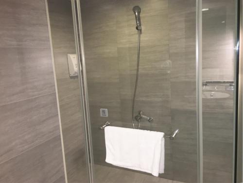 a shower with a glass door with a white towel at Xinshe Hotel - Hsinchu in Hsinchu City