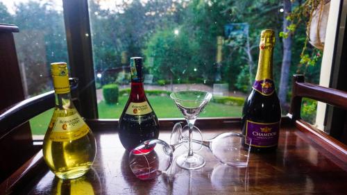 three bottles of wine and glasses on a table at LUSHOTO EXECUTIVE LODGE in Lushoto