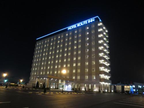 a hotel building with a blue sign on top of it at Hotel Route Inn Minami Yokkaichi in Yokkaichi