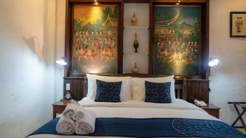 a bedroom with a bed with a painting on the wall at Cheva Gallery Boutique Hotel in Chiang Mai