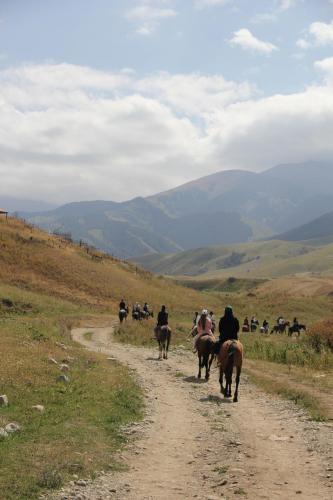 a group of people riding horses down a dirt road at Guest house CBT Chon-Kemin in Shabdan